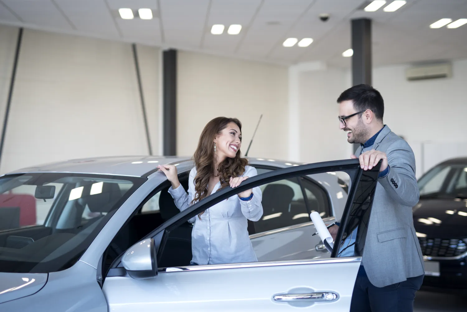 Customer viewing a car with a salesperson in a showroom